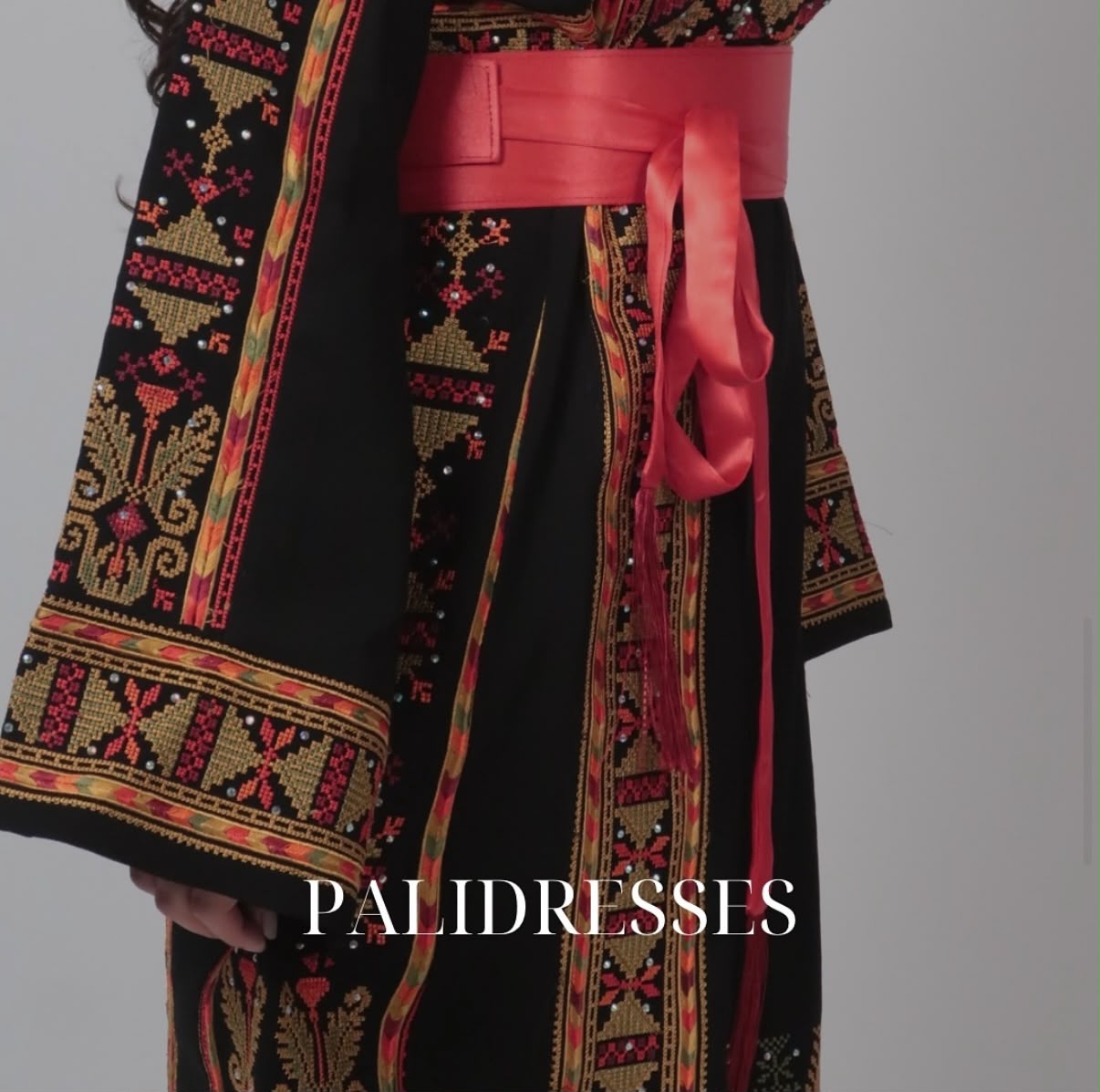 Detail van zwarte thobe met goud en rood tatreez
